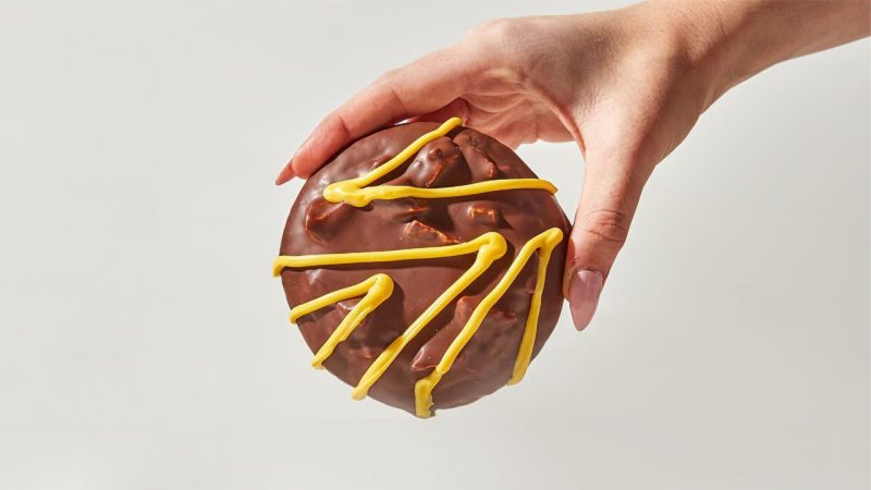 a hand from above holding a giant squiggle cookie